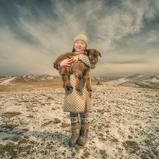 Herder holding a cashmere goat on the Mongolian steppe